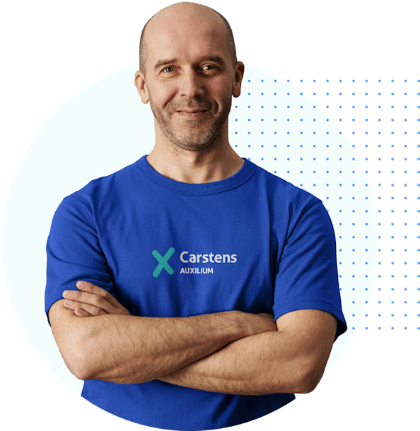 Ein freundlicher Mann mit Halbglatze und einem dunkelblauen T-Shirt lächelt mit verschränkten Armen in die Kamera. Ein freundlicher Mann mit Halbglatze und einem dunkelblauen T-Shirt lächelt mit verschränkten Armen in die Kamera.