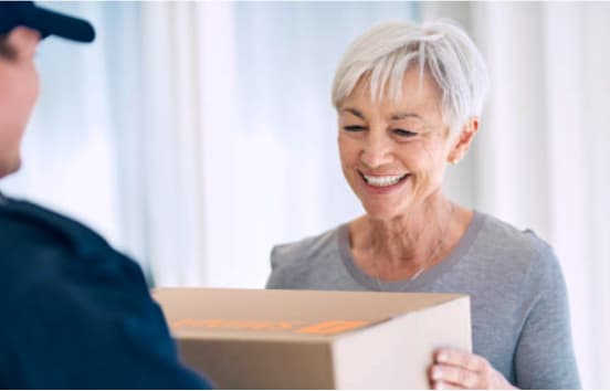 Ein Postbote übergibt ein Paket an eine Seniorin. Ein Postbote übergibt ein Paket an eine Seniorin.
